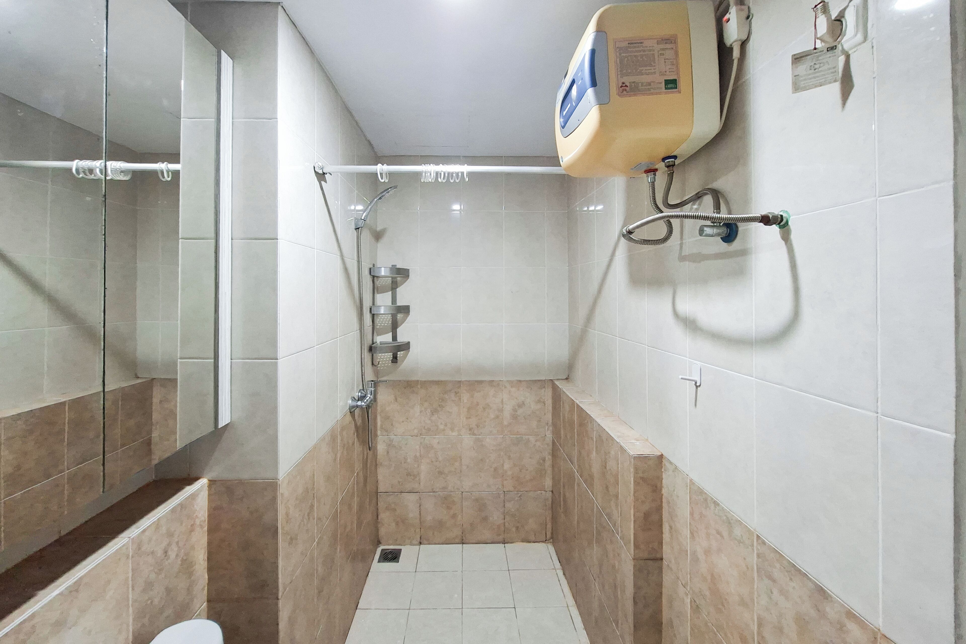 A small, tiled bathroom with a shower, a toilet, and a mirror.