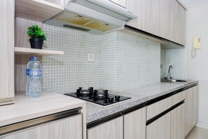 Uma cozinha com fogão a gás, pia, planta em vaso e dispenser de água.