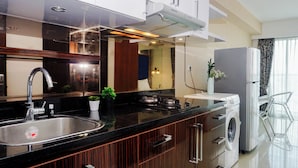 Una cocina moderna con un lavabo de acero inoxidable, lavadora integrada y un espejo grande sobre el mostrador.