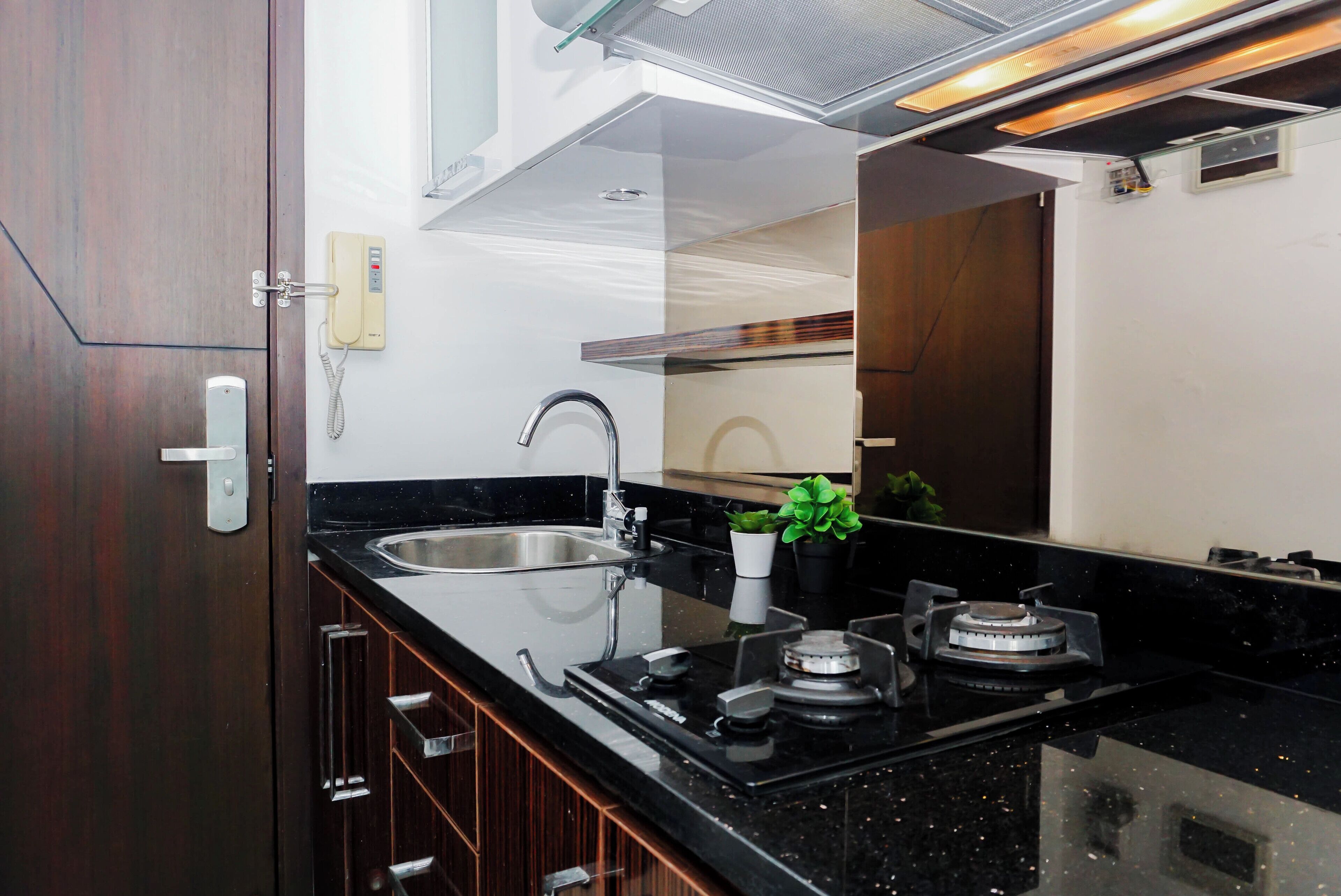 Una cocina moderna con un lavaplatos integrado, grifo de acero inoxidable y estufa a gas.