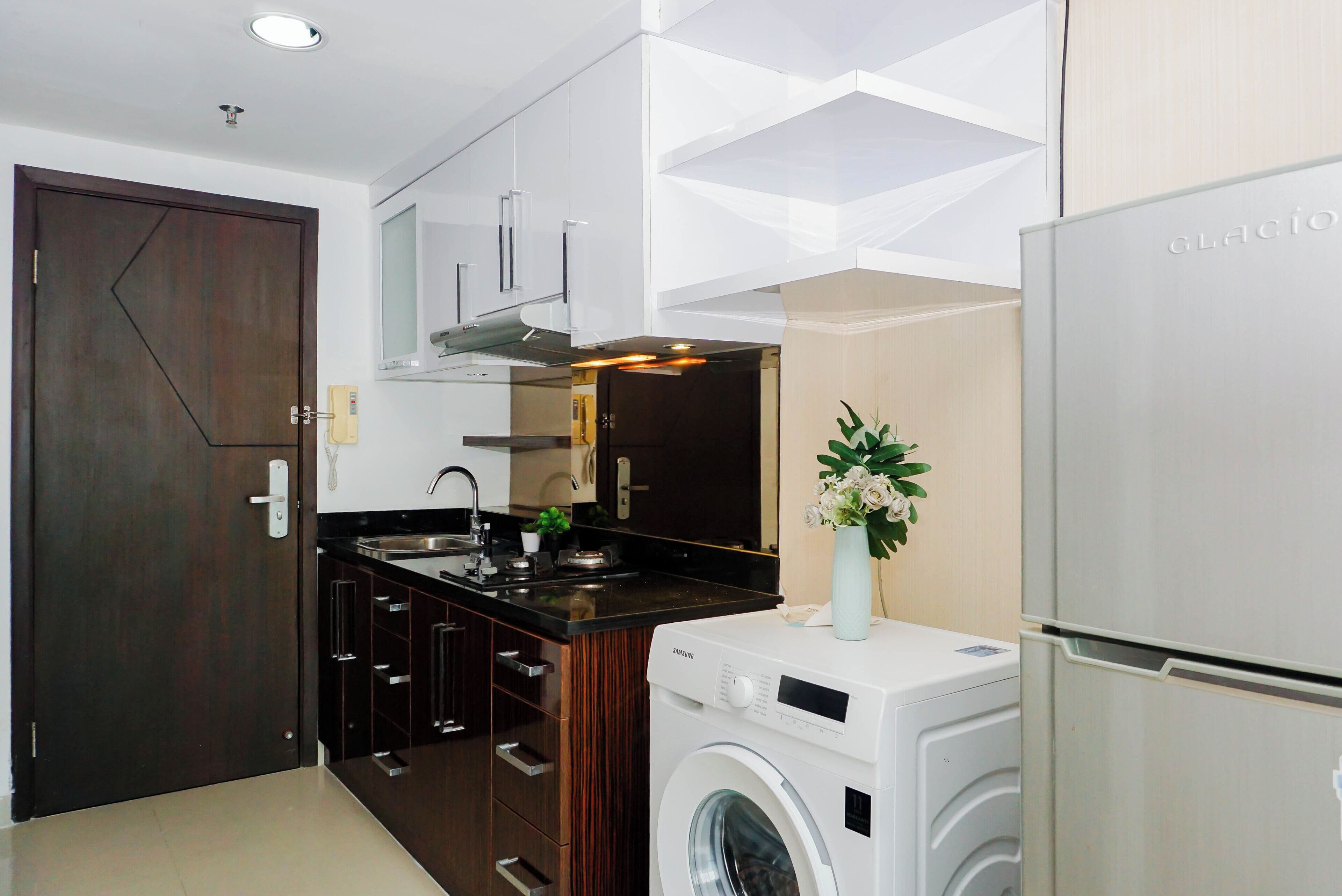 Una cucina moderna con lavatrice, frigorifero e una porta in legno scuro.