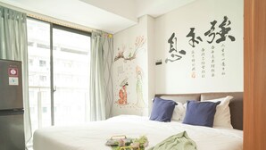 Ein Hotelzimmer mit einem Bett, einem Kühlschrank, einem Fenster mit Vorhängen und einer Wand mit chinesischer Kalligrafie.
