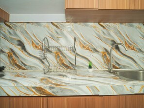 Cozinha com painel de mármore, pia de aço inoxidável e armários de madeira.