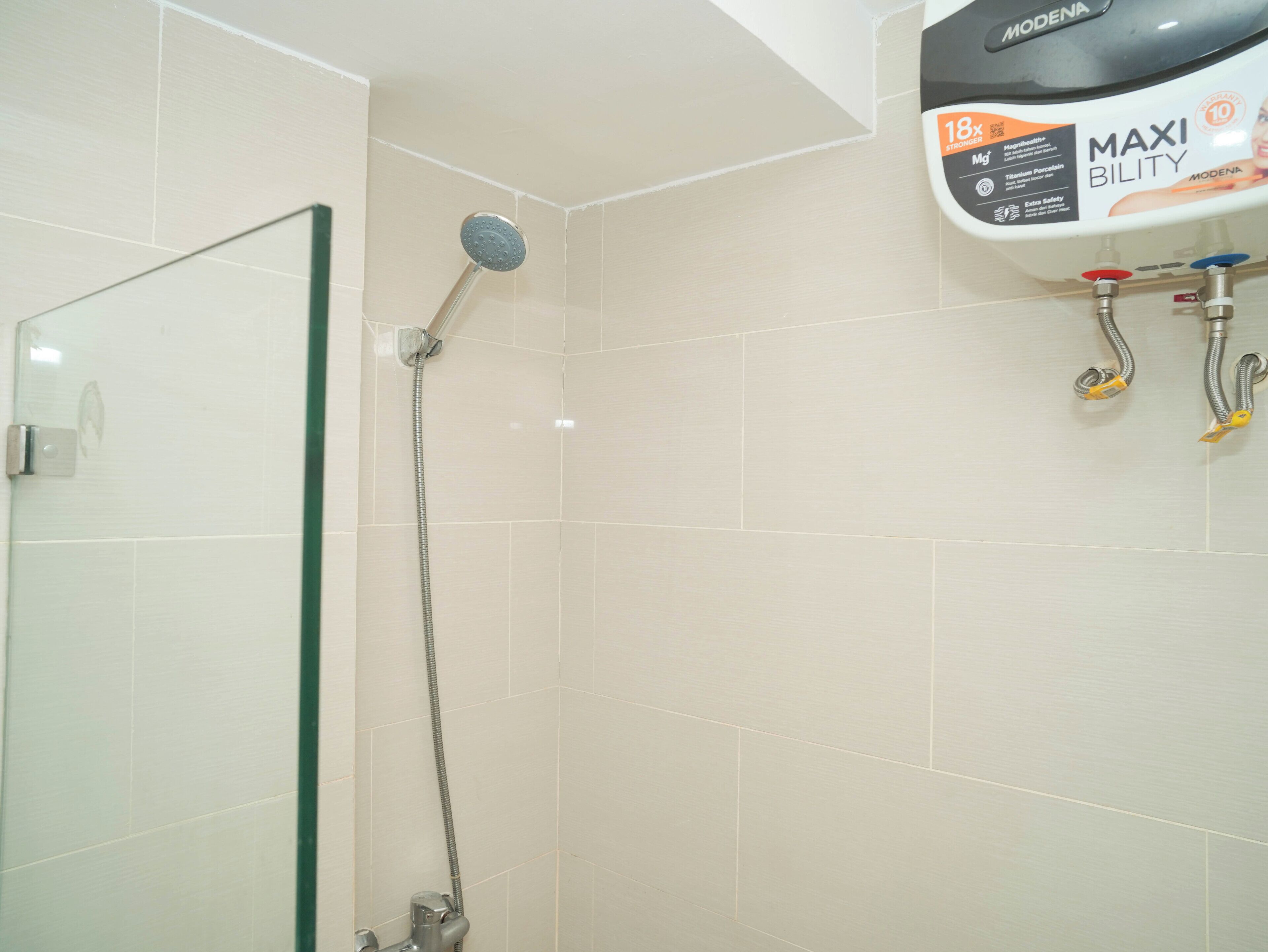 Une salle de bain avec une douche, une porte en verre et un chauffe-eau fixé au mur.
