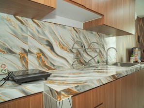 Uma cozinha com painel de parede de mármore, pia de aço inoxidável e armários de madeira.
