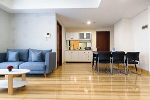 A modern living room with a sofa, coffee table, and dining area with chairs. - 6 Pax Tranquil 3Br With Extra Room At Grand Sungkono Lagoon Apartment (Surabaya)