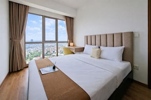 Une chambre d’hôtel avec un grand lit, un bureau, une chaise et une vue sur le paysage urbain grâce à de grandes fenêtres.