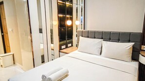 A hotel room with a bed, a bedside table, a wardrobe, and a mirror. - Best Deal And Comfy Studio At Delft Ciputra Makassar Apartment (Makassar)