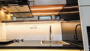 A modern kitchen with a built-in oven, stainless steel sink, and a range hood. - Best Deal And Comfy Studio At Delft Ciputra Makassar Apartment (Makassar)