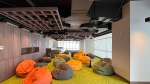 A modern interior with bean bags, a wooden wall, and a large window. - Best Deal And Comfy Studio At Delft Ciputra Makassar Apartment (Makassar)