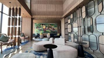 Een moderne lobby met een groot abstract schilderij, comfortabele zithoeken en een vloer met een patroon.