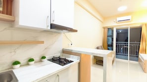 Cozinha moderna com fogão a gás, armários brancos e bancada de madeira.
