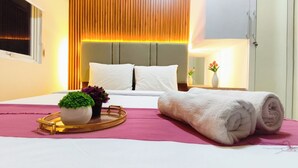 A hotel room with a bed, pillows, a bedside table with a vase, a tray with a plant, and a rolled towel. - Serene 2Br For 3 Pax At Tanglin Supermall Mansion Apartment (Surabaya)