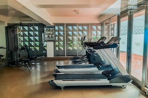 Un gimnasio con cintas de correr, máquinas de pesas y un muro de cristal con vistas.