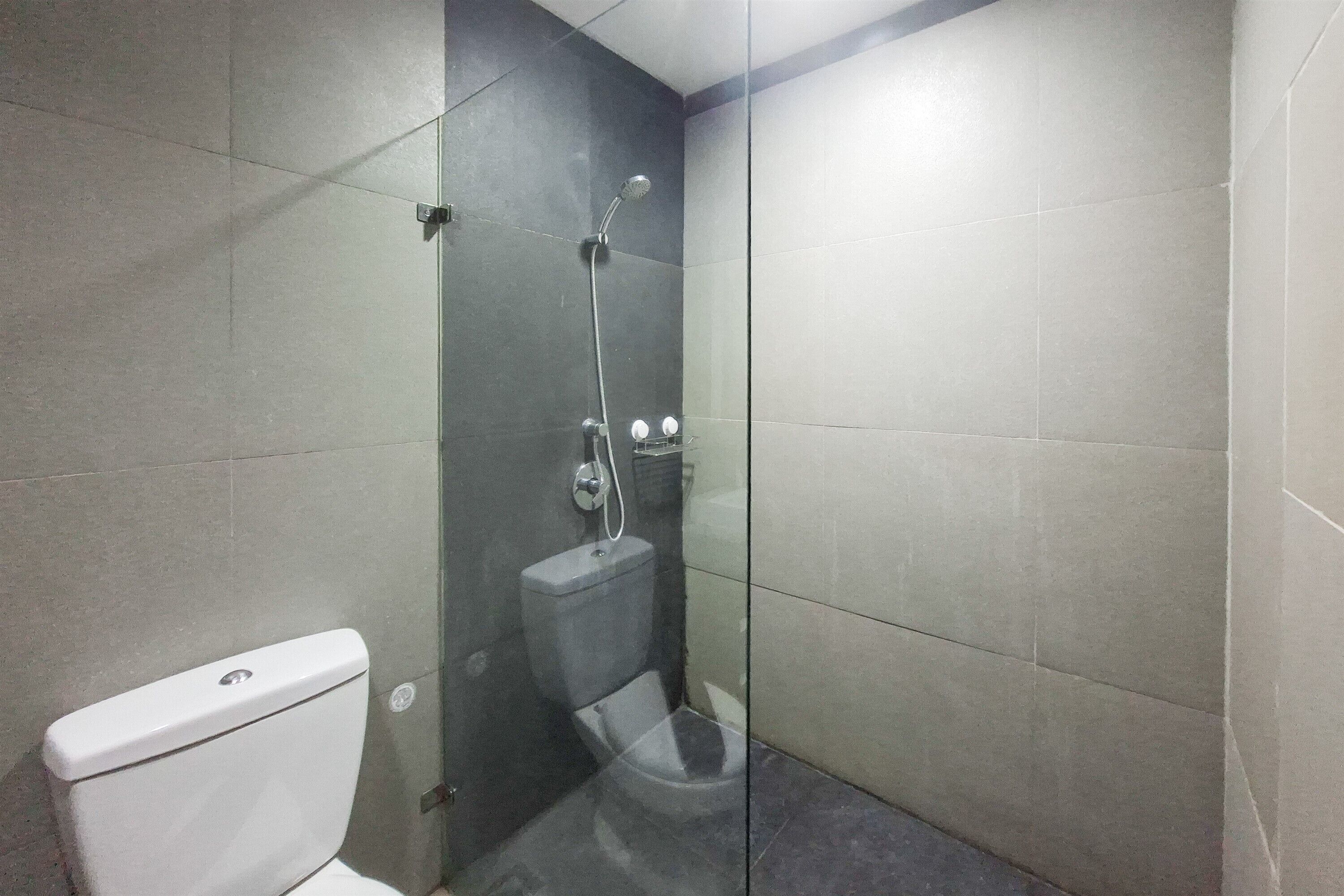 A bathroom with a toilet, a shower, and a glass partition.