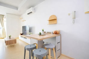 A modern kitchen with a wooden table, two stools, a built-in oven, and a wall-mounted phone. - Strategic And Cozy 2Br Apartment At Fx Residence (Jakarta)