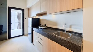 Uma cozinha moderna com bancada de granito preto, pia de aço inoxidável e armários de madeira.