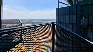 Un bâtiment moderne doté d’un balcon en métal qui offre une vue sur le paysage urbain.