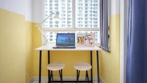 A workspace with a laptop, a desk lamp, and two stools. - Warm And Simple Studio At Cinere Bellevue Suites Apartment (Depok)