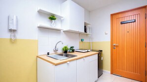 A kitchen with a built-in sink, a wall-mounted phone, and a wooden door. - Warm And Simple Studio At Cinere Bellevue Suites Apartment (Depok)