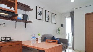 A modern kitchen with a gas stove, a dining table with chairs, a sofa, and a balcony with a view. - Tranquil And Comfy 2Br At Cinere Bellevue Suites Apartment (Depok)