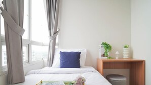 A neatly made bed with white bedding, a blue pillow, and a green throw. - Tranquil And Comfy 2Br At Cinere Bellevue Suites Apartment (Depok)