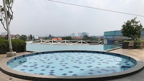 Une piscine dotée d’une terrasse carrelée, entourée d’une clôture et d’arbres.