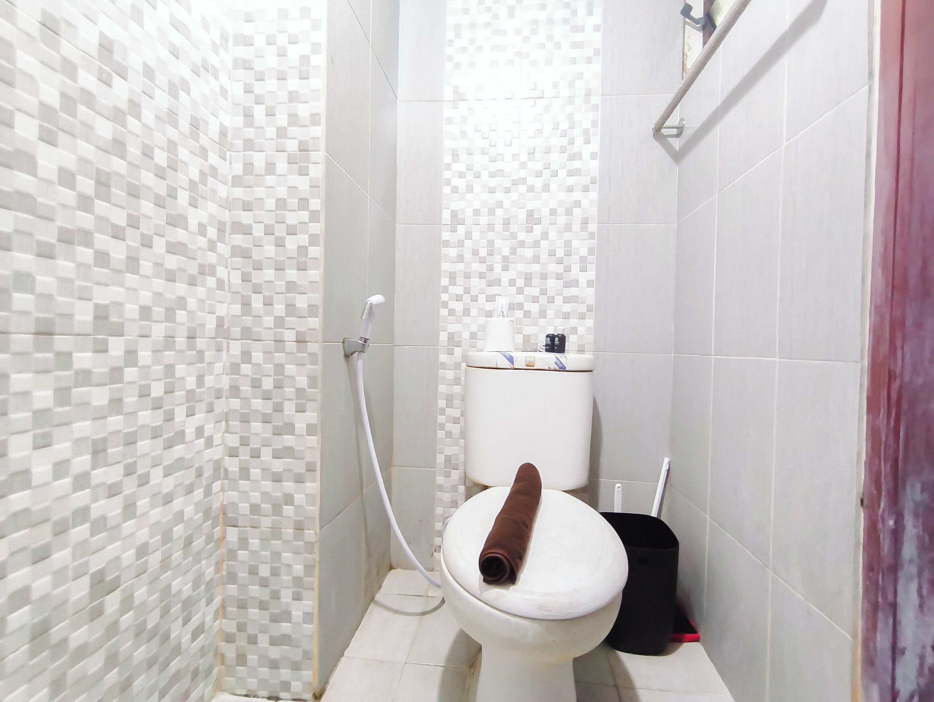 Kylpyhuone, jossa on wc, suihku ja laatoitettu seinä.