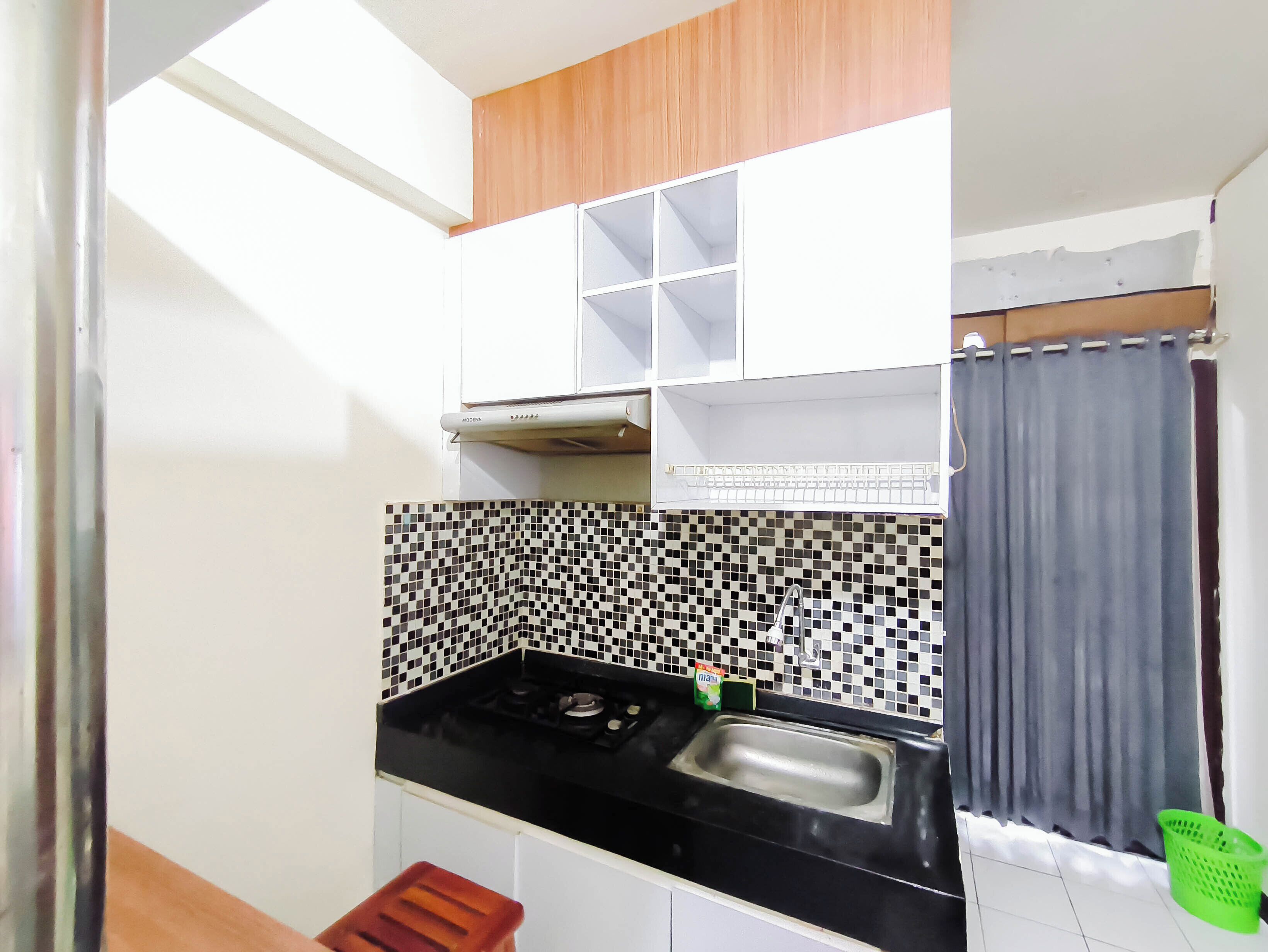 A compact kitchen with a black countertop, a sink, and a tiled backsplash.