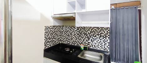 A compact kitchen with a black countertop, a sink, and a tiled backsplash.