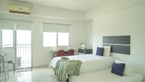 A modern hotel room with a bed, a desk, a chair, and a window. - Studio Apartment At Park View Condominium (Depok)