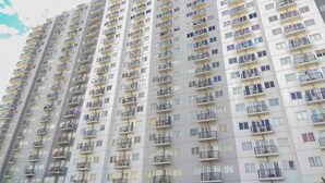 A high-rise residential building with multiple balconies, each with a small window and a metal railing. - Studio Apartment At Park View Condominium (Depok)