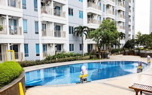 A modern apartment building with balconies, a swimming pool, and surrounding greenery. - Studio With Good Location At Orchard Supermall Mansion Apartment (Surabaya)