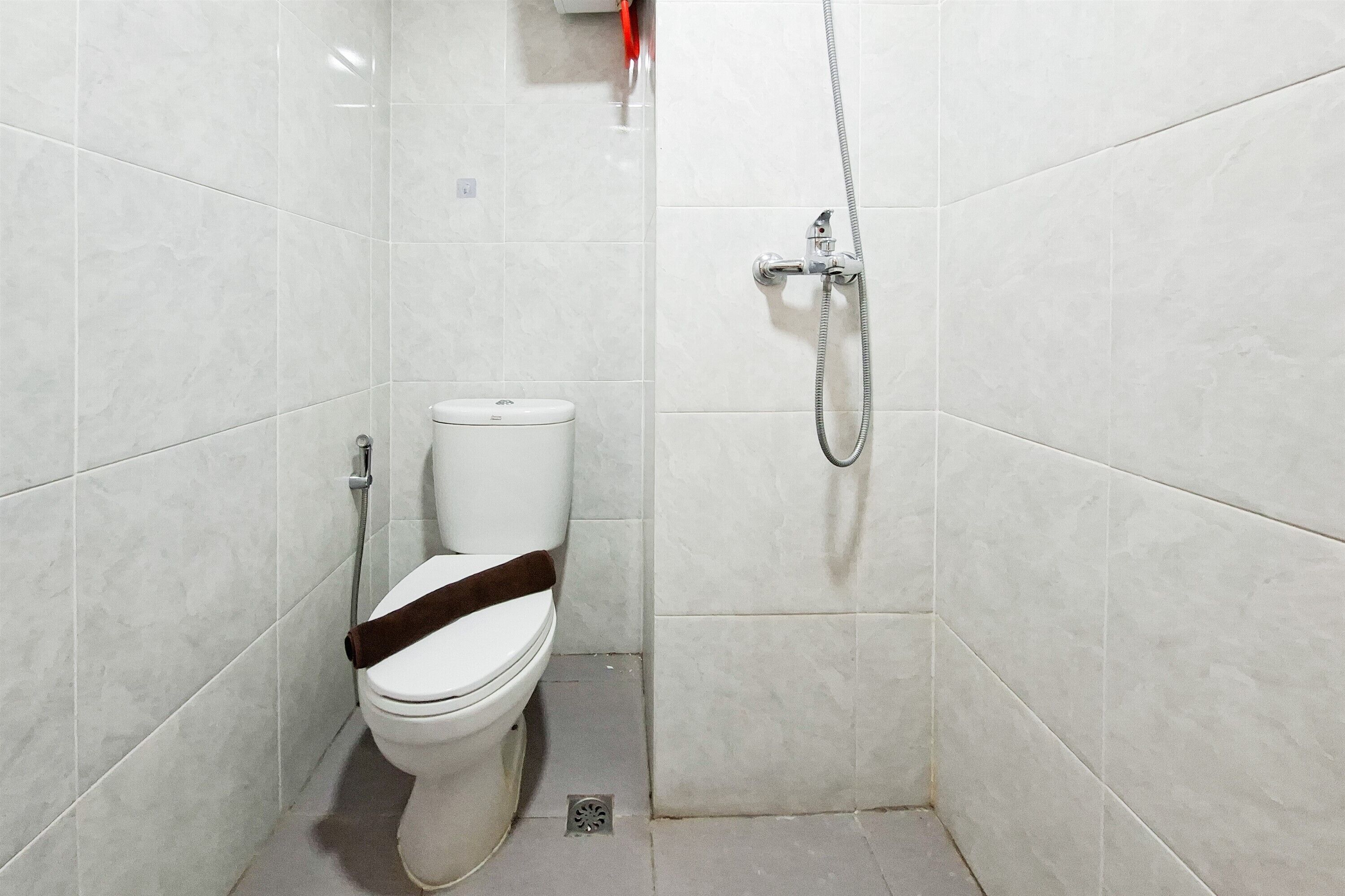 A small, tiled bathroom with a toilet, a shower, and a drain.