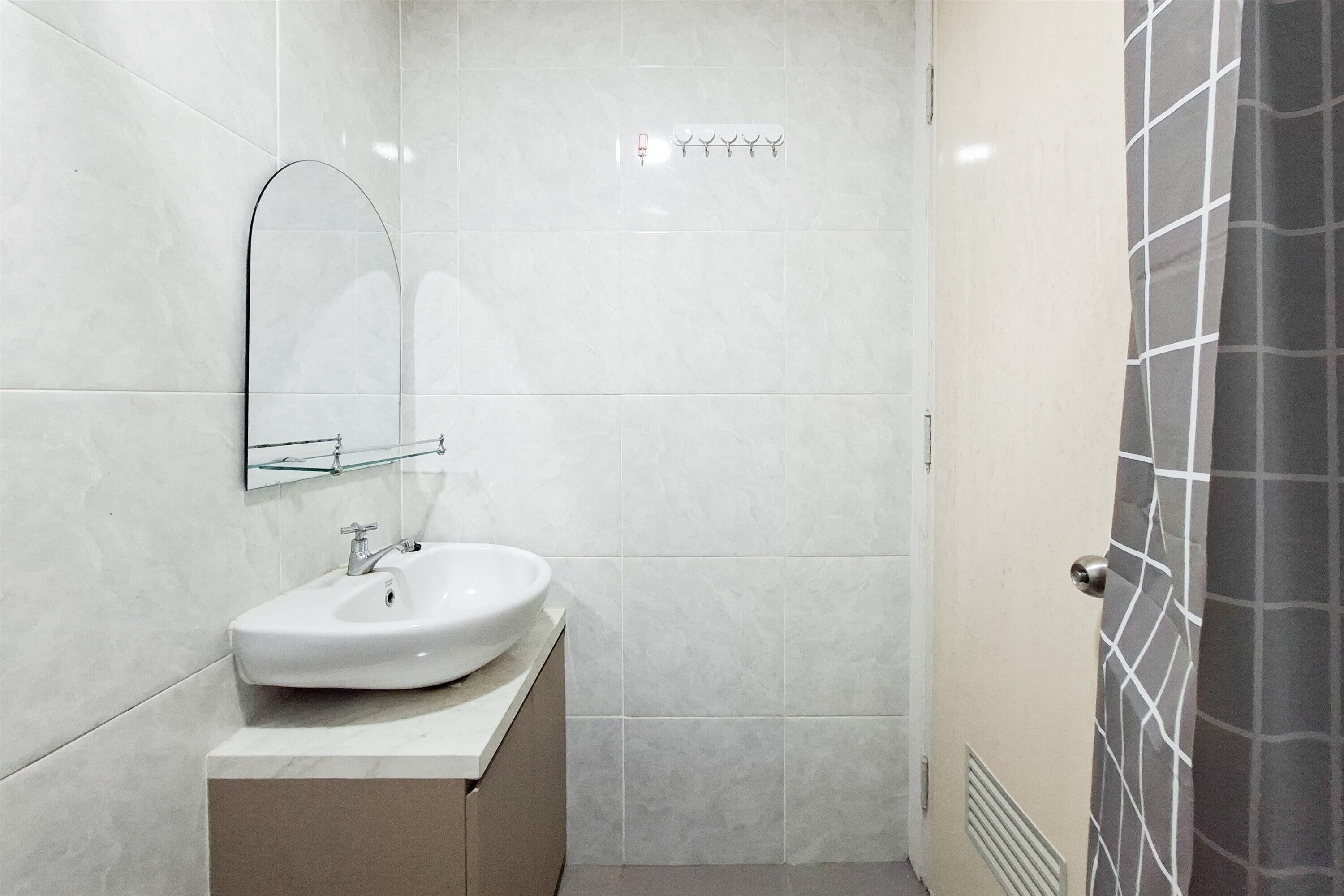 Casa de banho com lavatório branco, espelho e porta-toalhas.