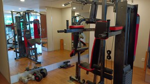 Un gimnasio con equipamiento de levantamiento de pesas, un espejo y suelo de madera.