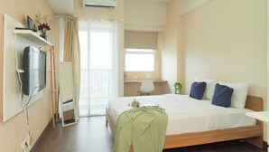 Habitación de hotel con cama, escritorio, silla, televisor y aire acondicionado.