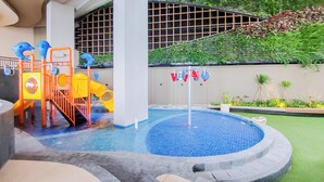 Ein Schwimmbecken mit Wasserrutsche, Spielbereich und einer Fontäne.