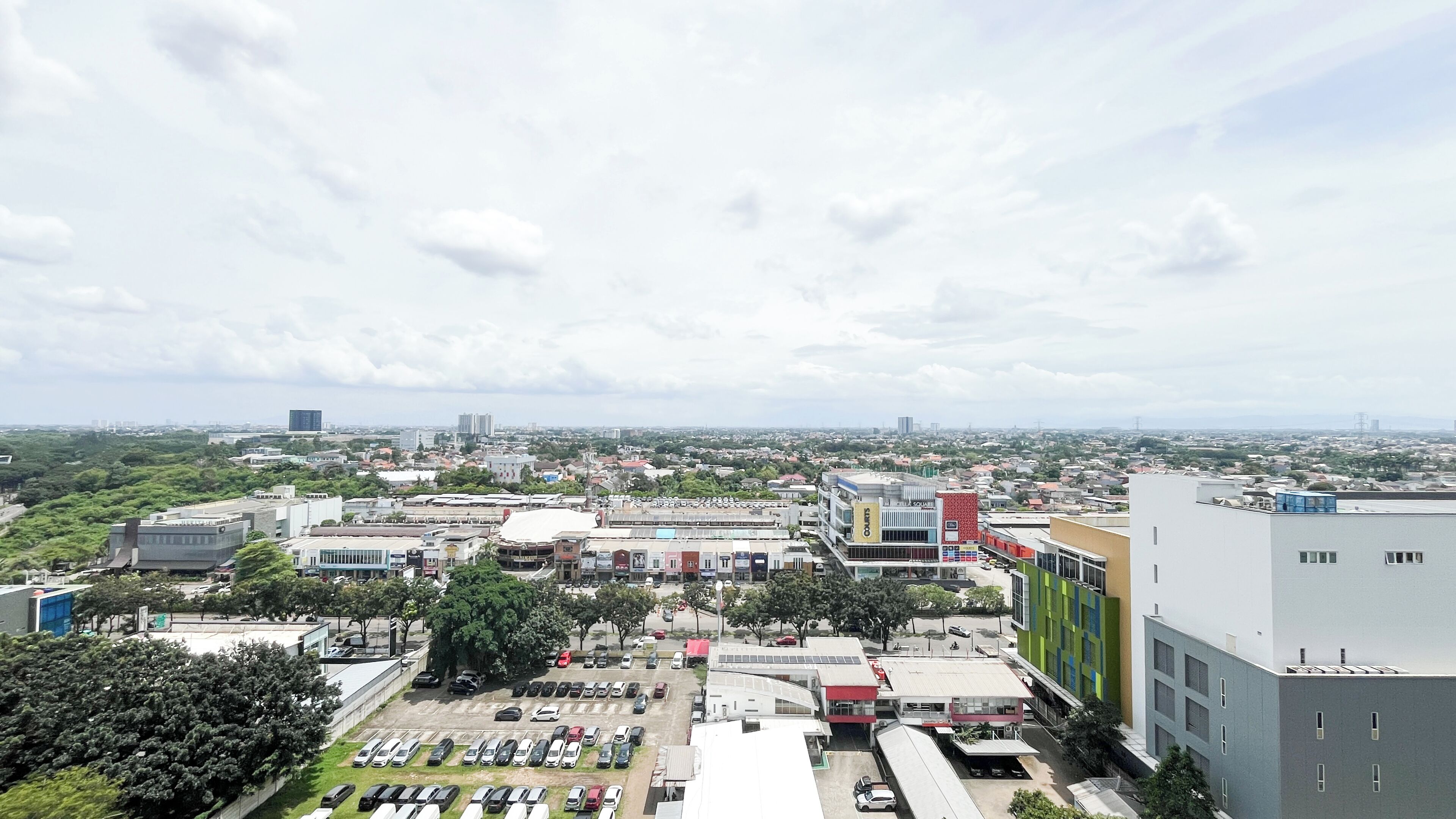 A cityscape with a mix of modern and older buildings, a parking lot, and a view of distant city skyline.