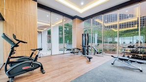 Ein Fitnessstudio mit Trainingsgeräten, großen Fenstern und Holzboden.