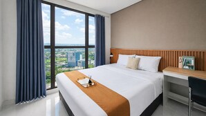 Habitación de hotel con una cama grande, un escritorio y vistas a la ciudad.