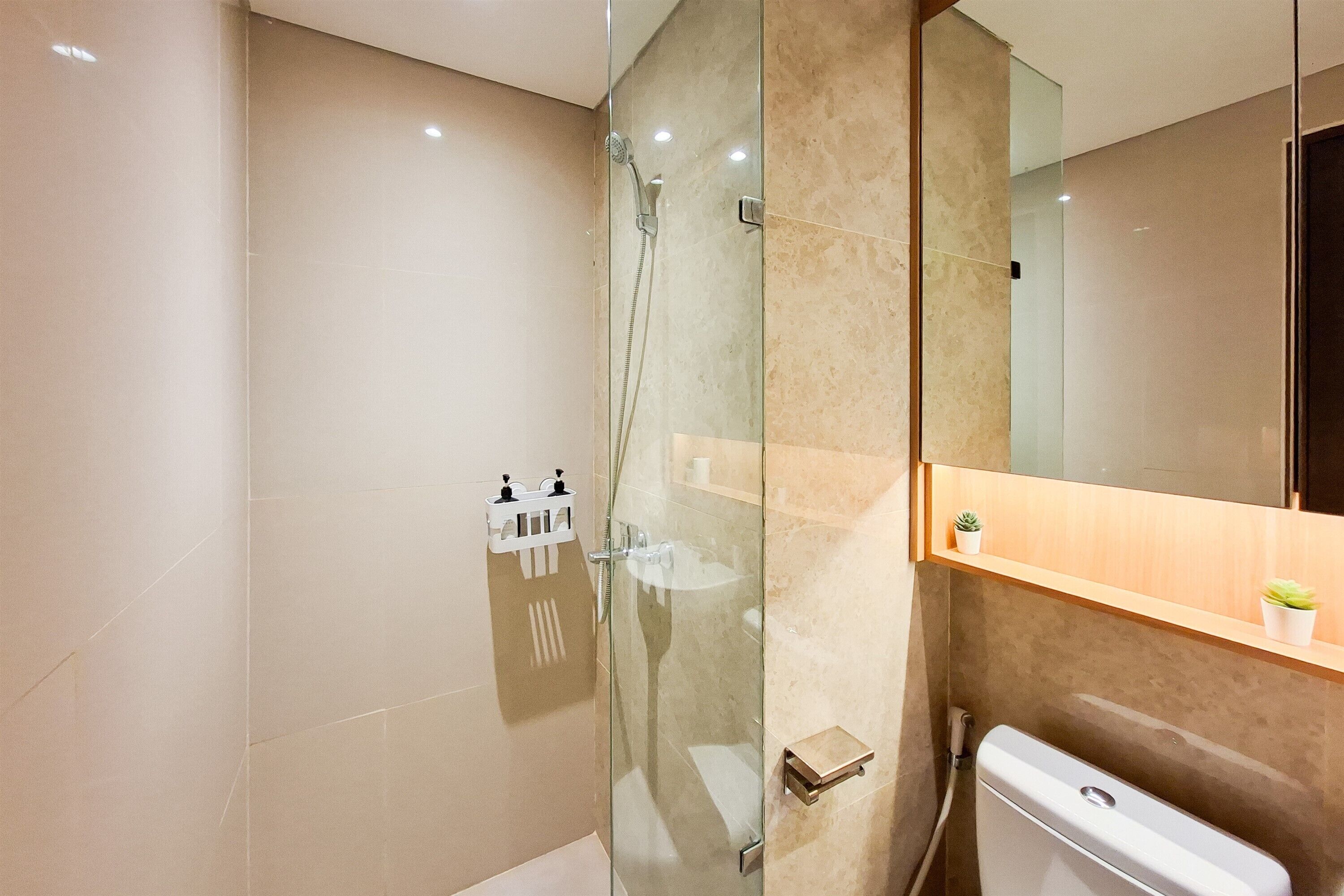 A modern bathroom with a glass shower enclosure, a toilet, and a sink.