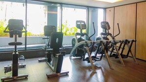 A gym with various exercise equipment, large windows, and a wooden wall. - Chic And Roomy 2Br Space At Apartment Casa Grande Residence (Jakarta)