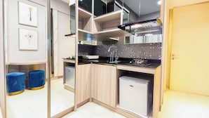 Cozinha compacta com bancada preta, pequena geladeira e pia com torneira moderna.
