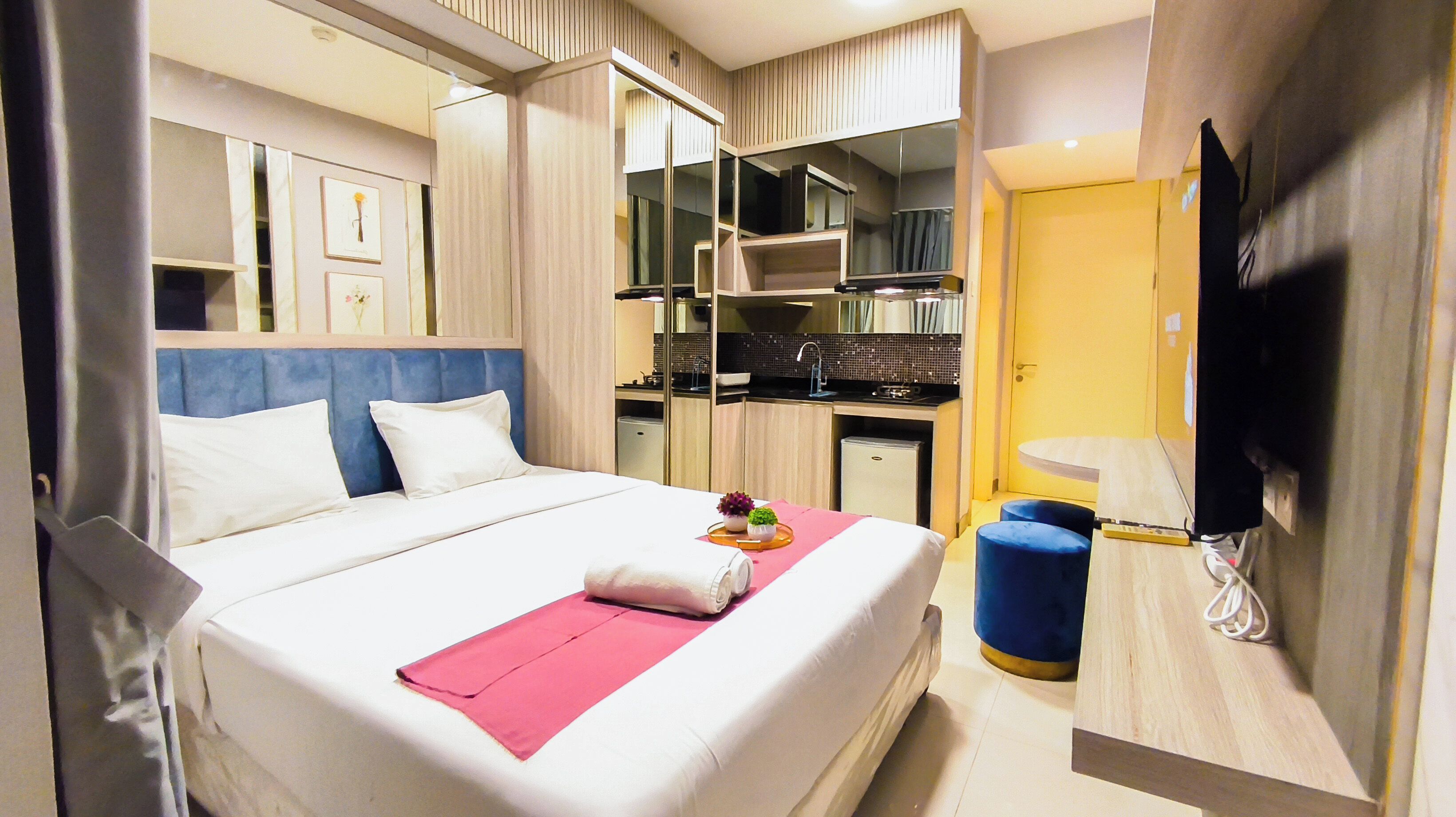 Ein Hotelzimmer mit Bett, Schreibtisch, Spiegel und Fernseher.