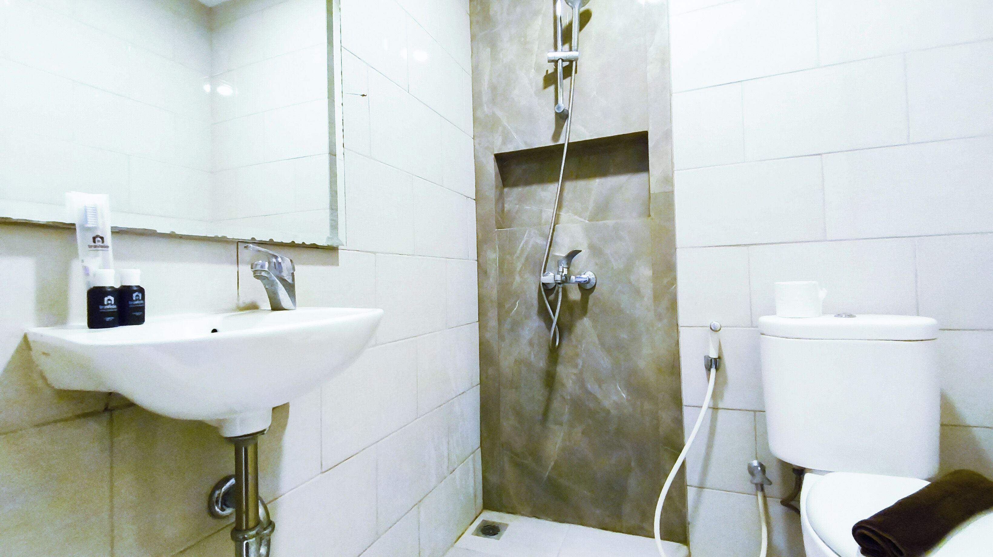 A bathroom with a sink, mirror, shower, and toilet.