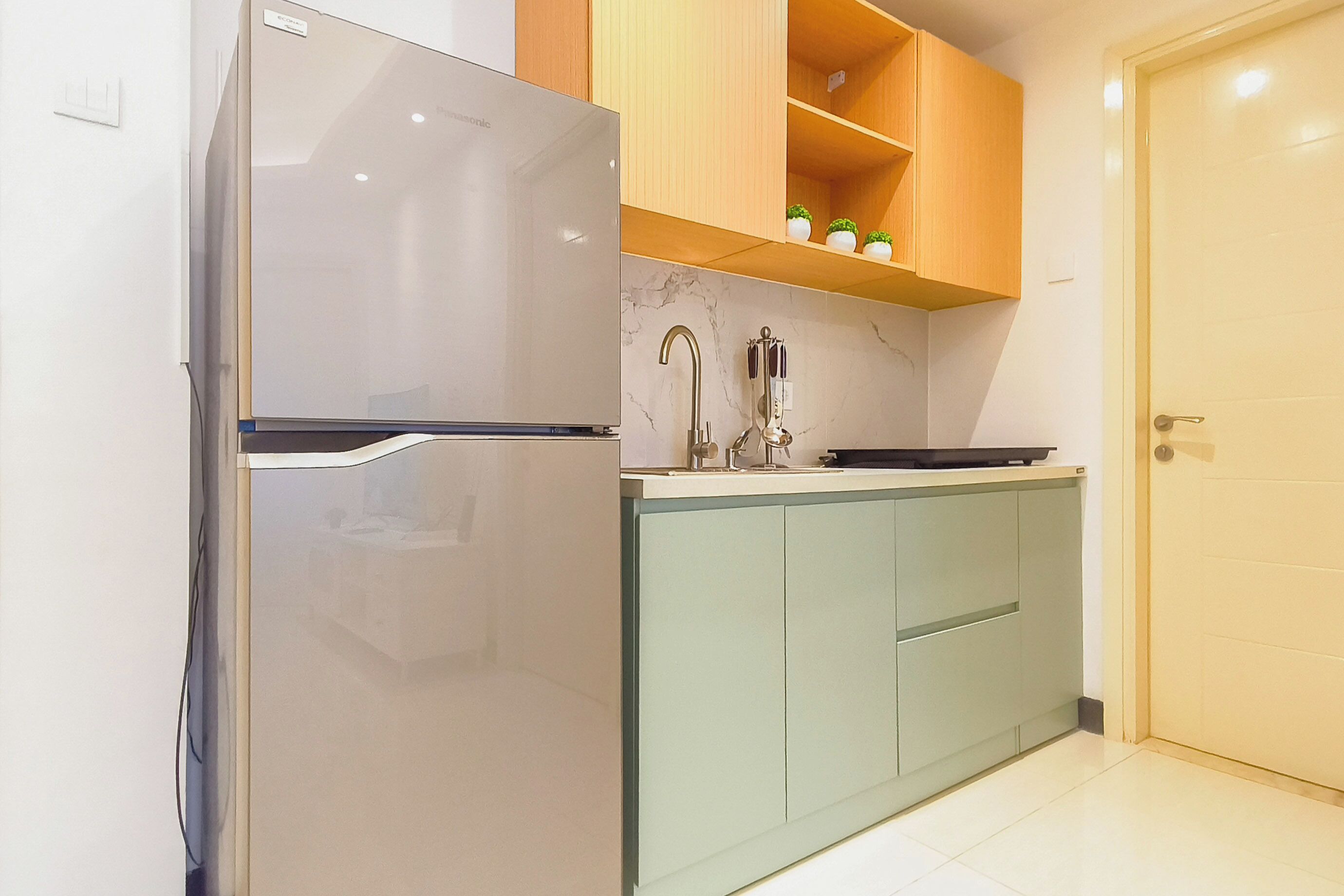 A kitchen with a refrigerator, a sink, and wooden cabinets.