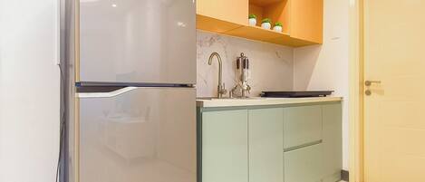 A kitchen with a refrigerator, a sink, and wooden cabinets.