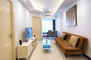 Ein modernes Wohnzimmer mit Sofa, Fernseher und Essbereich.