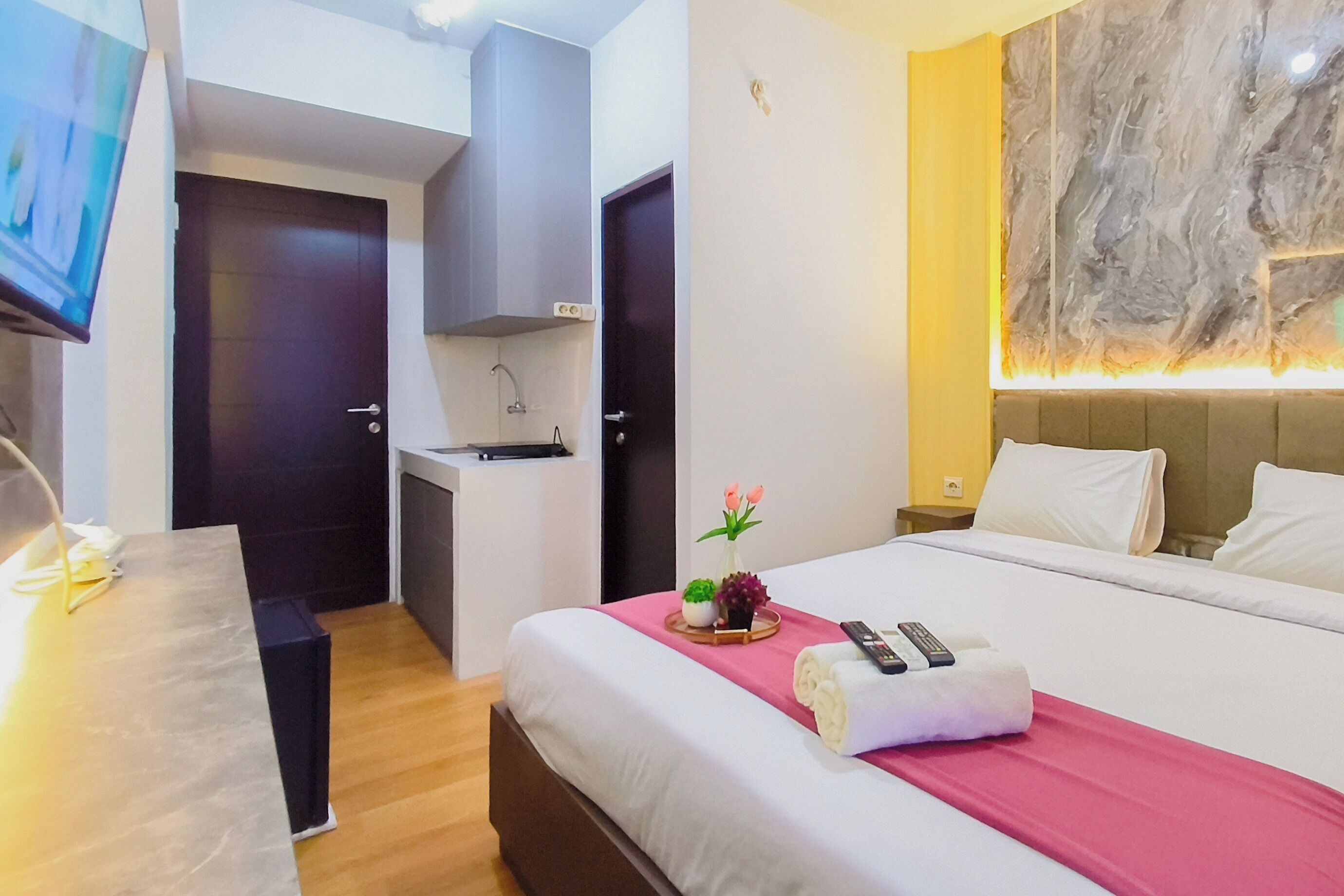A hotel room with a bed, a desk, a television, and a bathroom.
